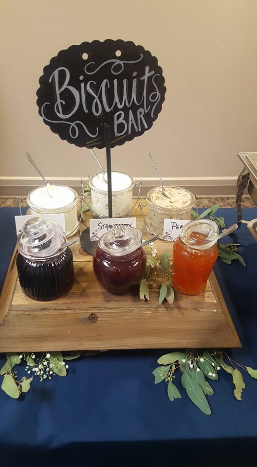 various jams and flavored butters with a sign that says Biscuits Bar